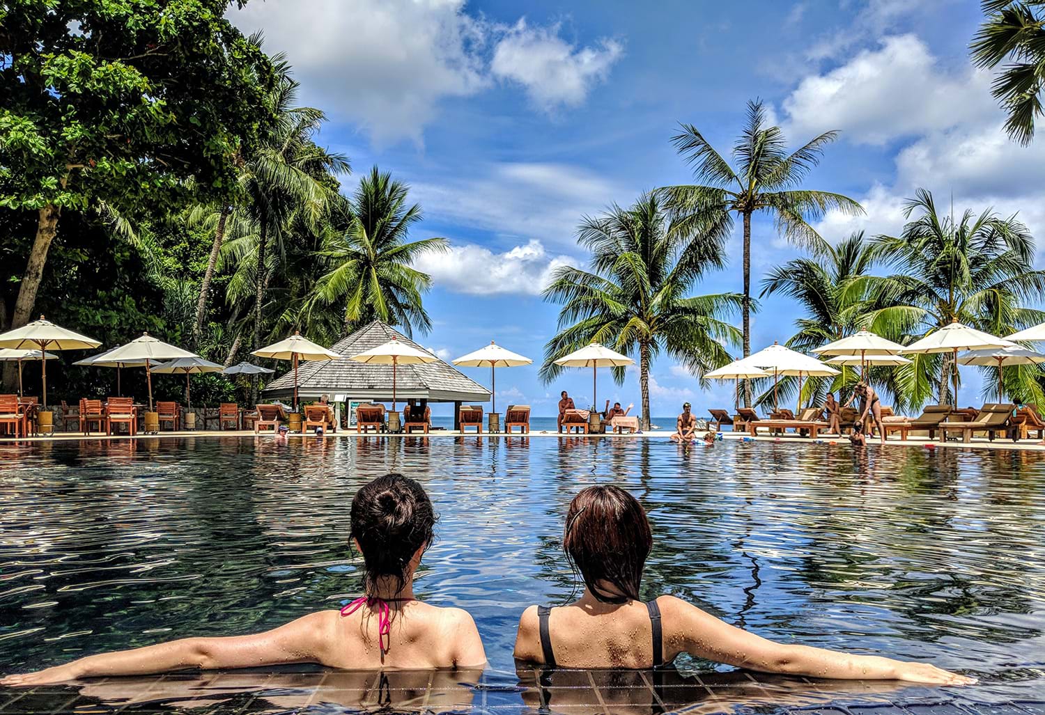 Two women sitting in pool at tropical resort