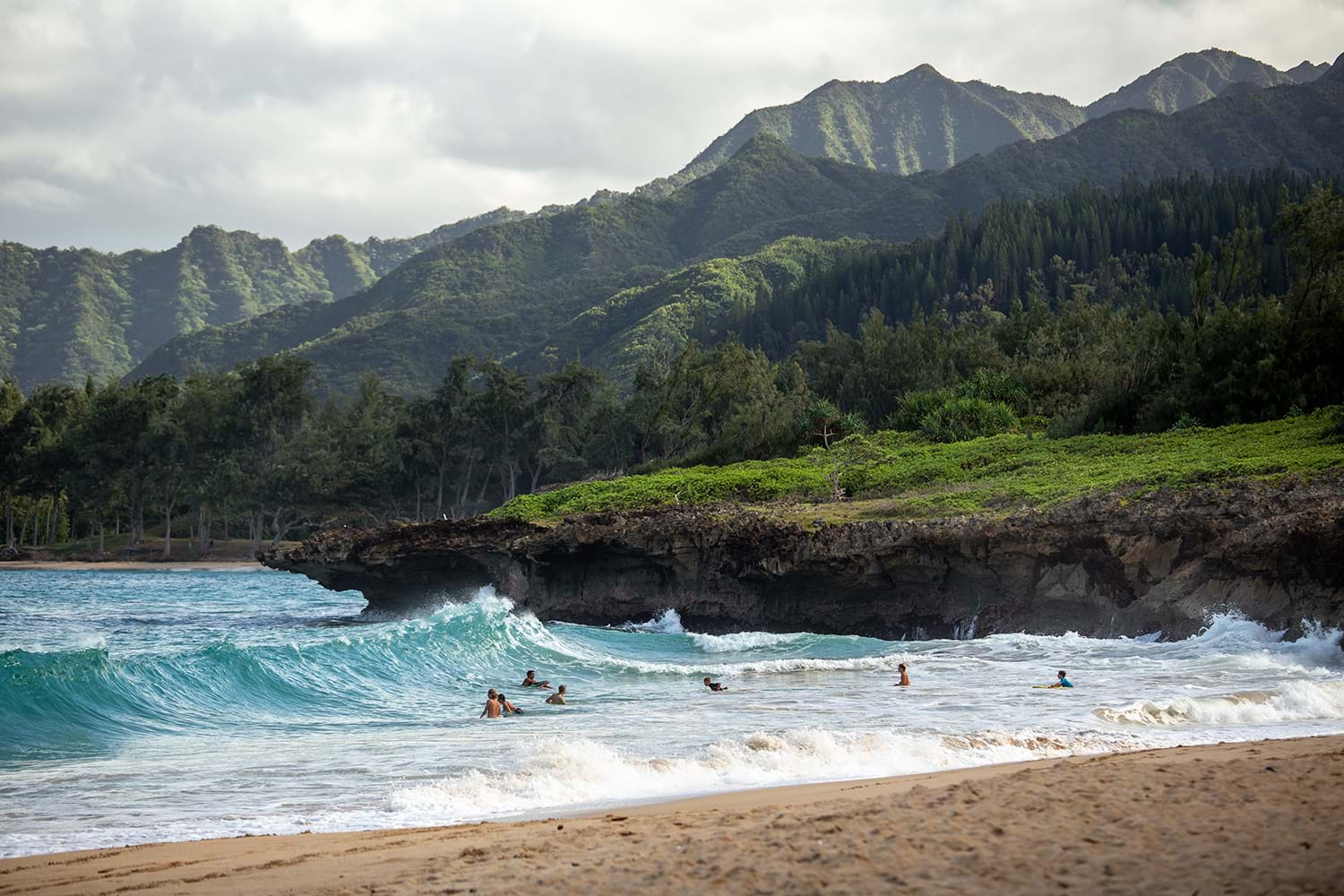 People playing in waves washing up against beach