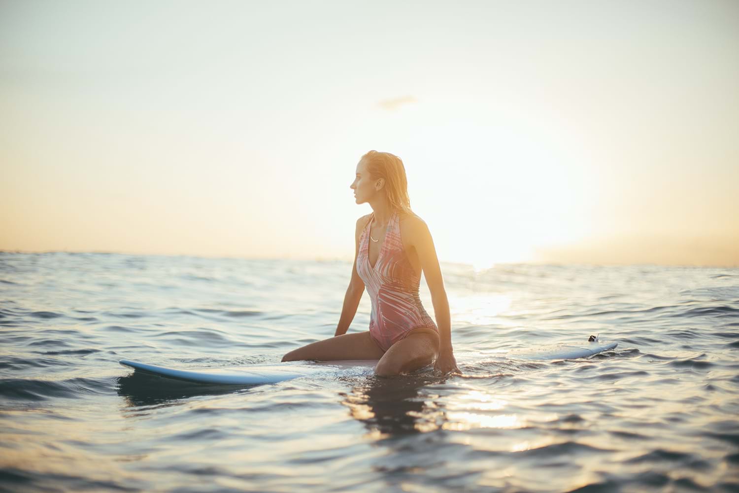Woman sitting on surfboard floating in water