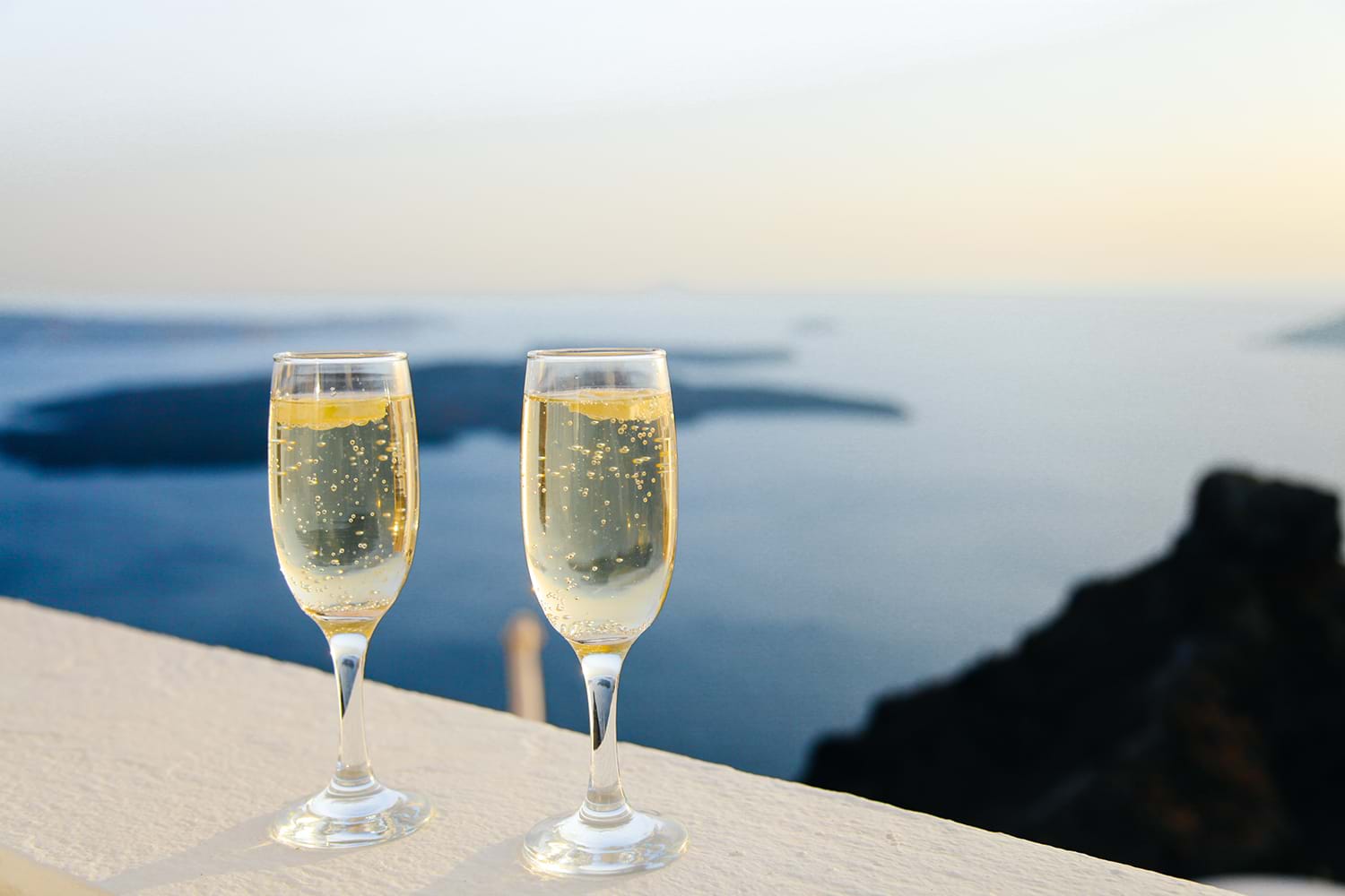 Two champagne glasses sitting on ledge overlooking view
