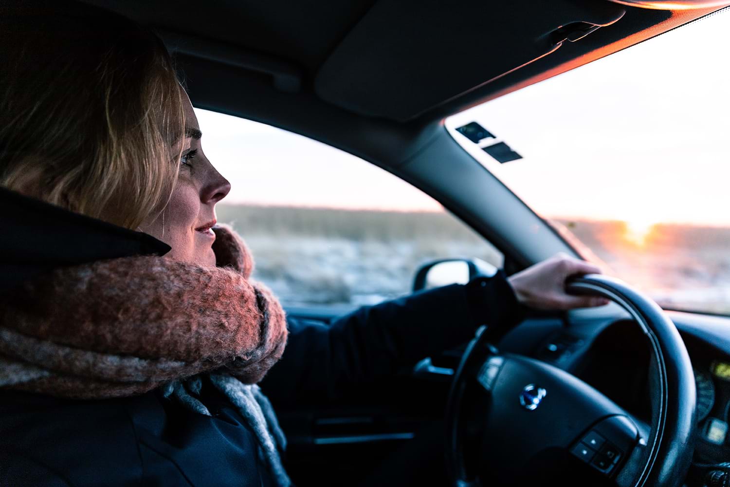 Woman in coat and scarf driving