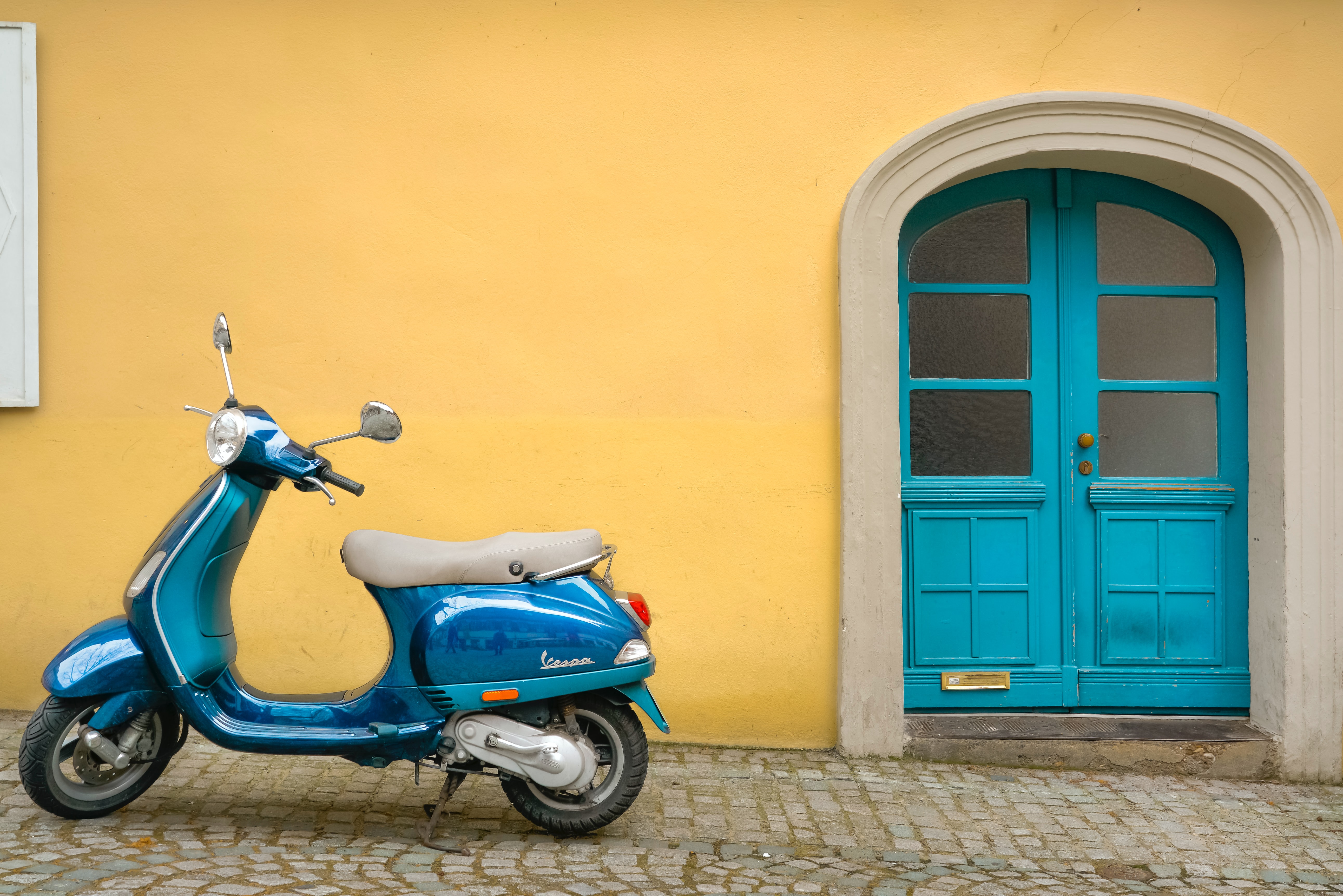 Vespa parked in front of yellow wall
