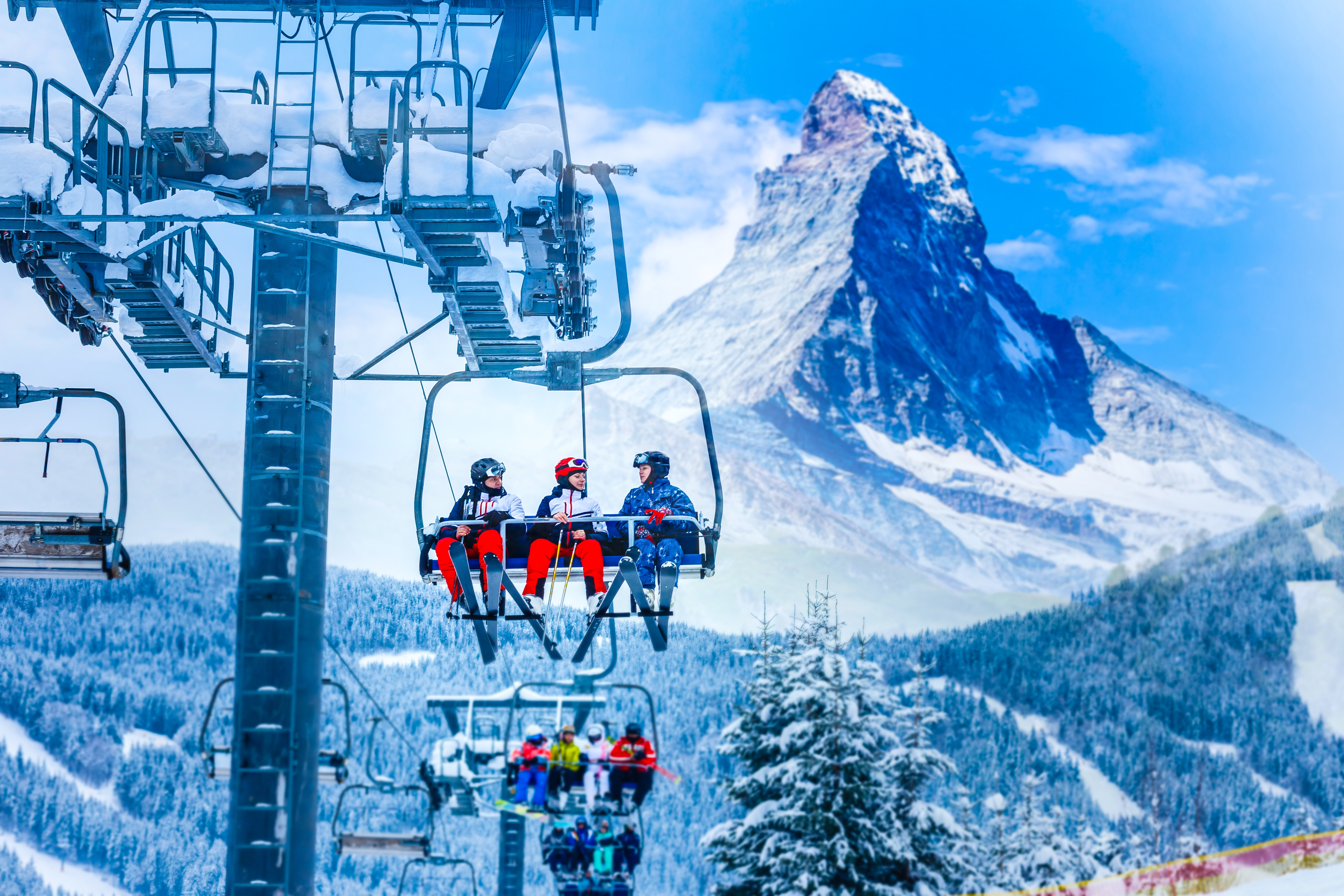 people on a chair lift at a ski resort with mountain in background