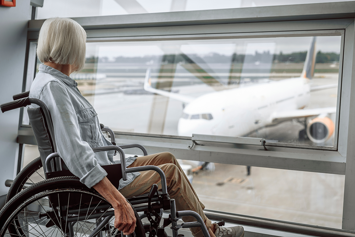 Woman in wheelchair looking out window at airplane