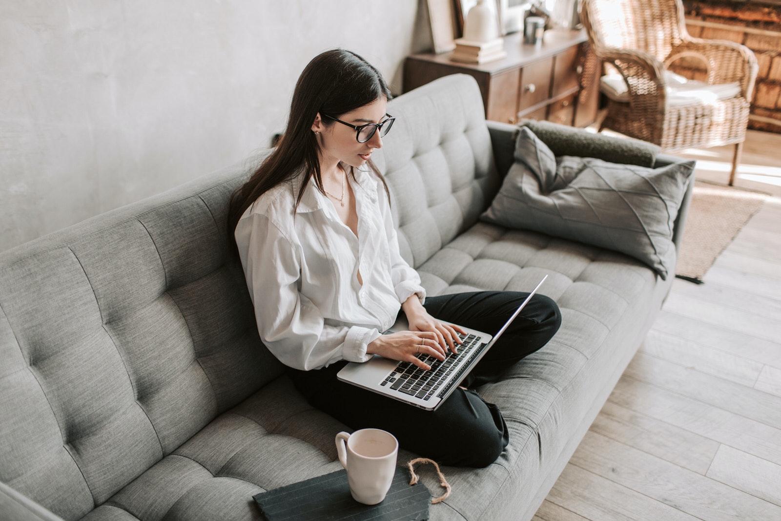A woman on a sofa using CRM software on her laptop to manage her photography business online.