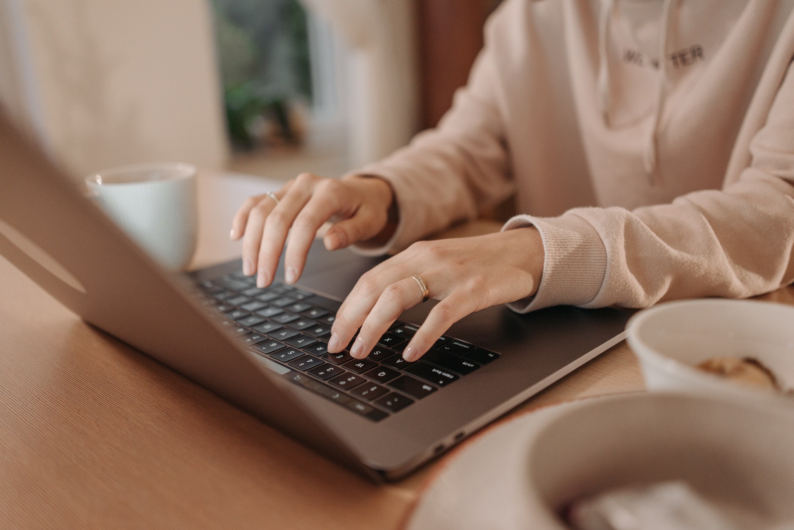 A woman photographer using laptop at home to back up photos with cloud storage.