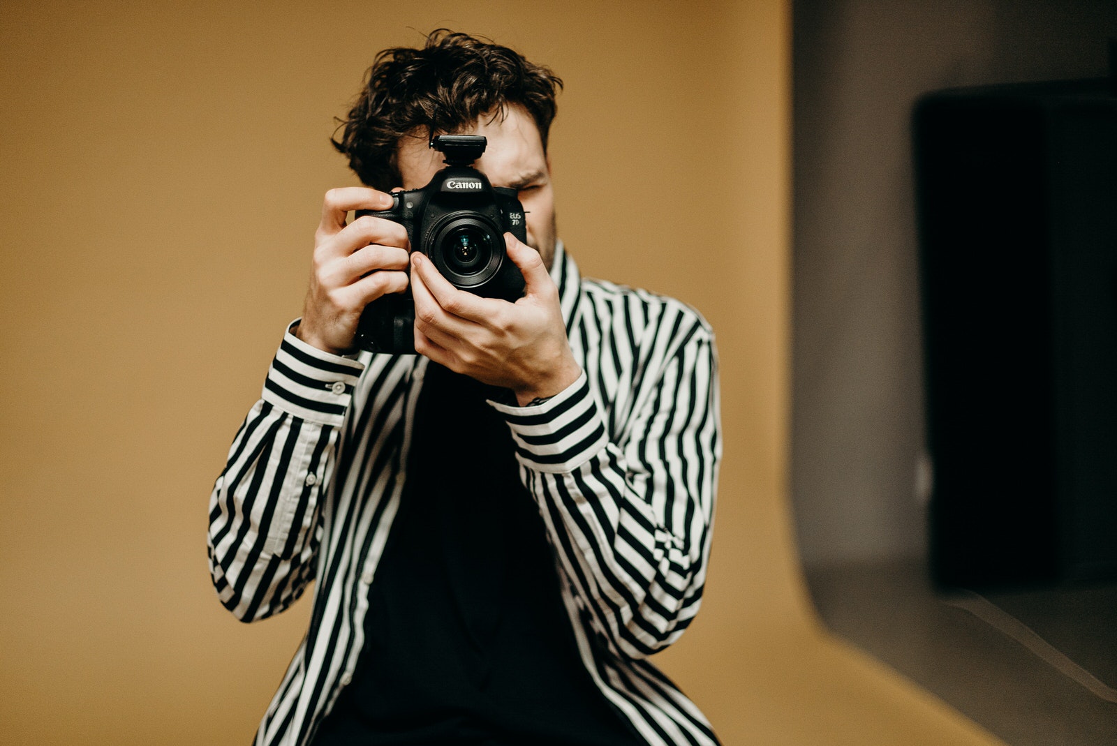 A photographer using a dual-slot Canon camera body for a studio photoshoot.