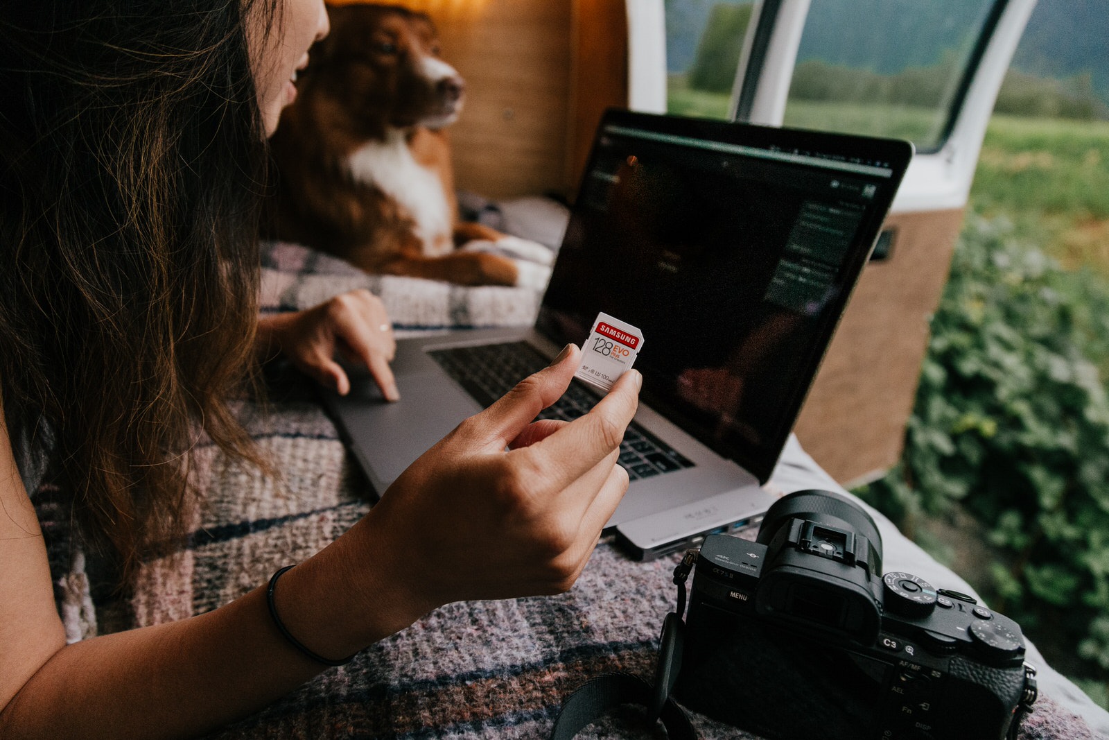 A woman photographer using an SD memory card to transfer her photoshoot files to a laptop.