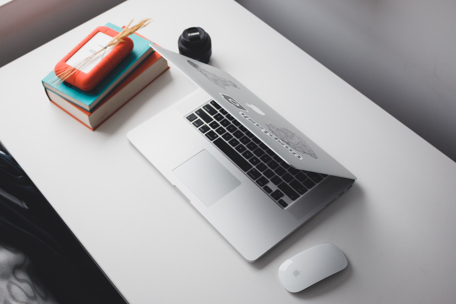 A portable Lacie external hard drive next to a photographer’s laptop and Canon camera lens.