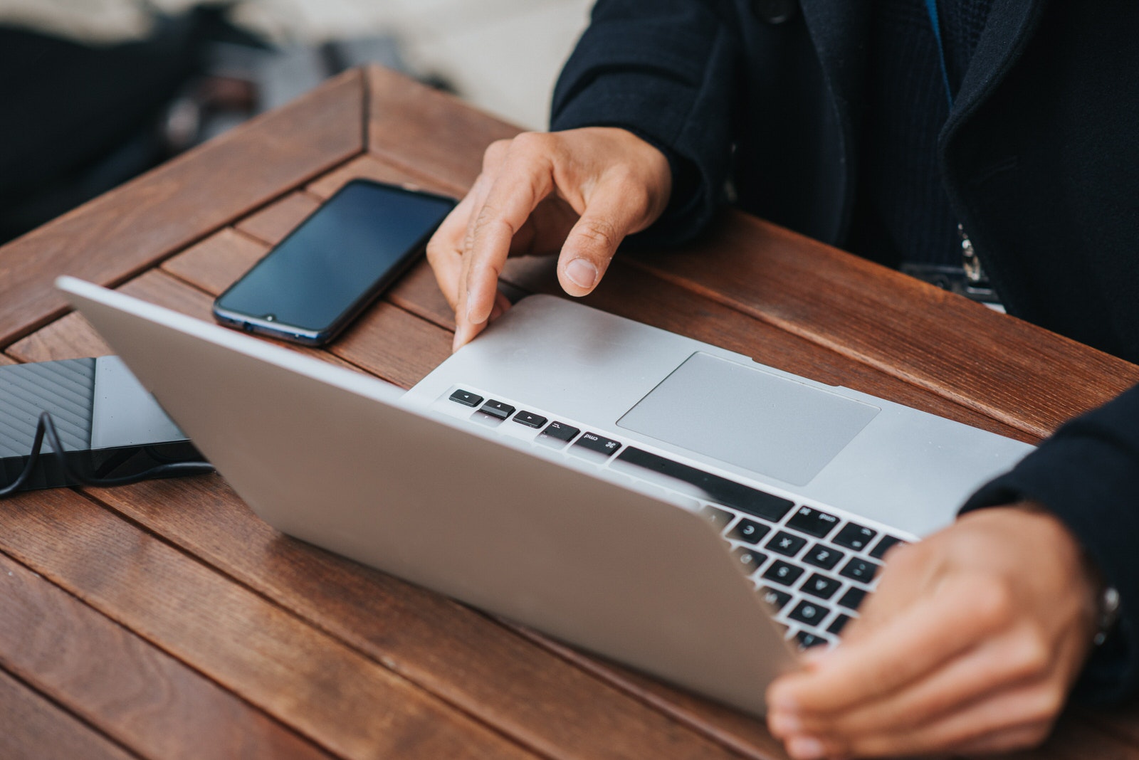 A photographer using an external HDD storage to transfer photos onto a MacBook laptop.