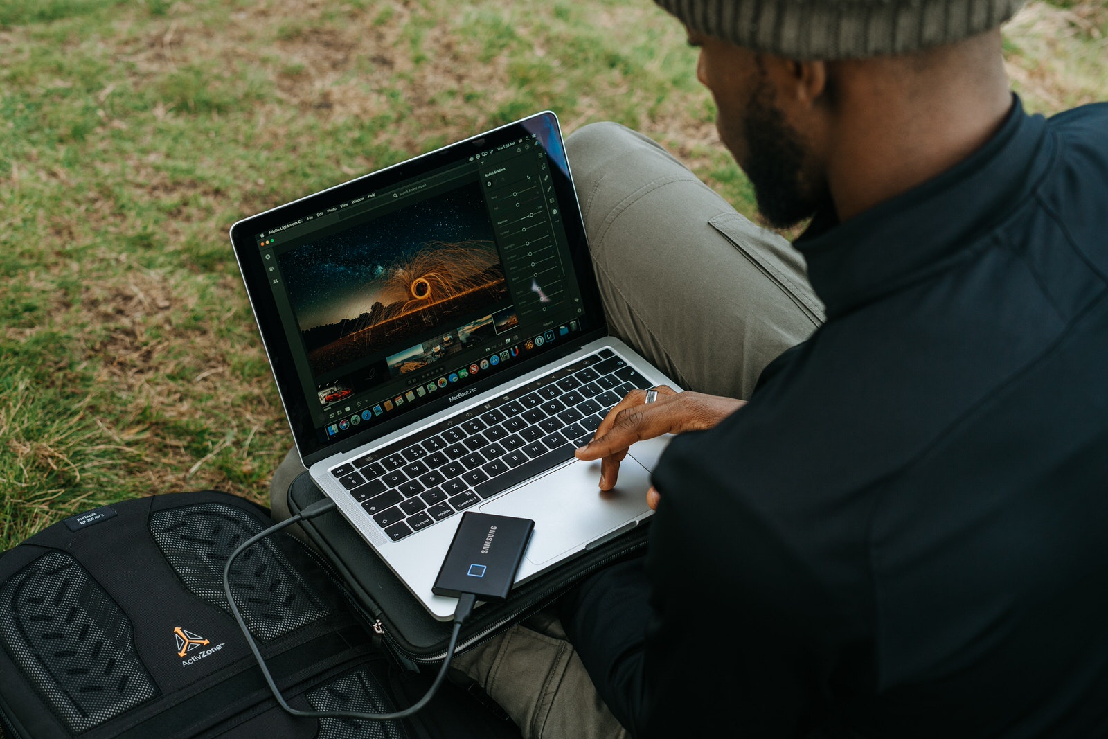 A photographer using an external drive connected to his MacBook to edit photos in Lightroom.