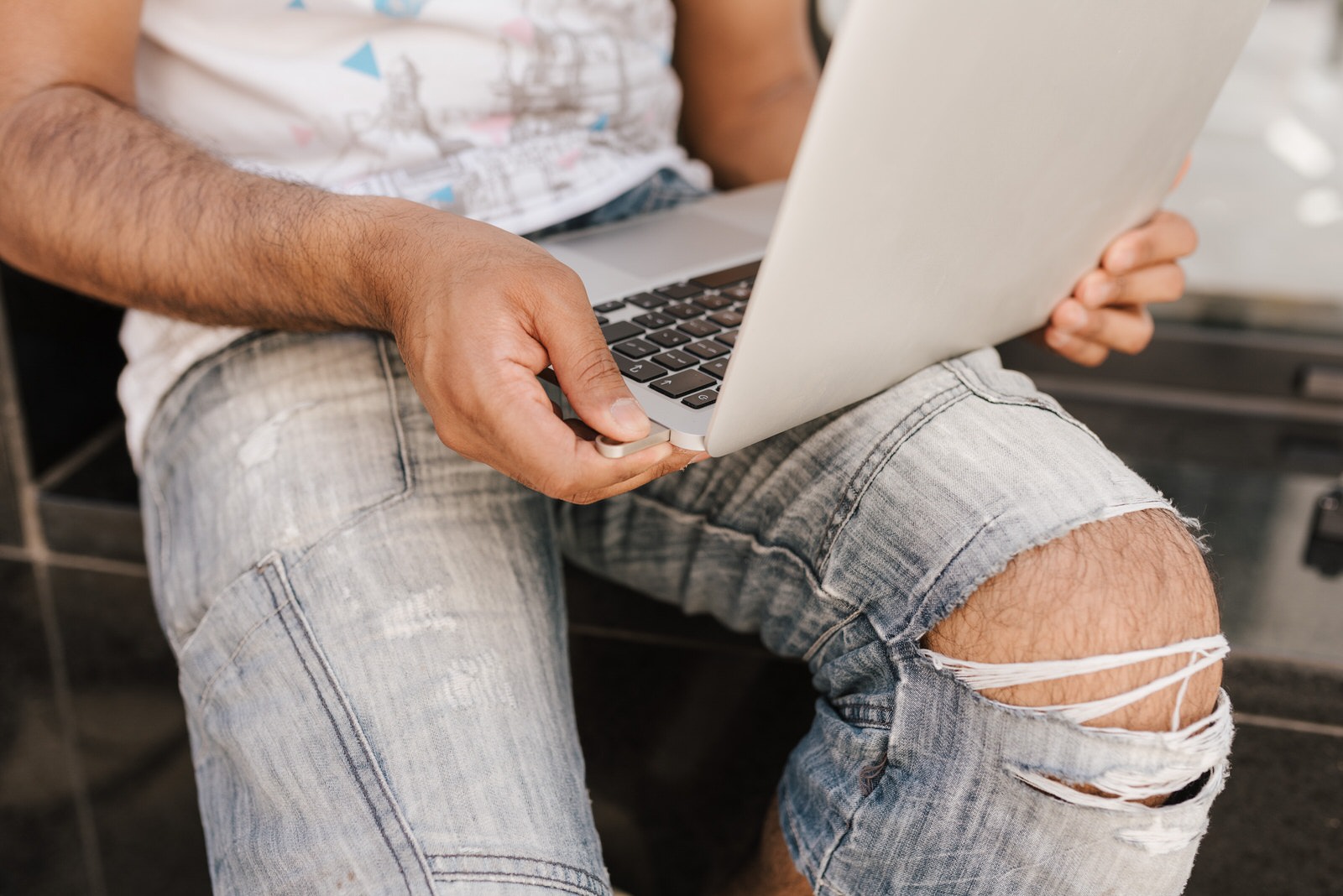 A photographer using a laptop with a USB stick plugged in to upload files on the cloud.