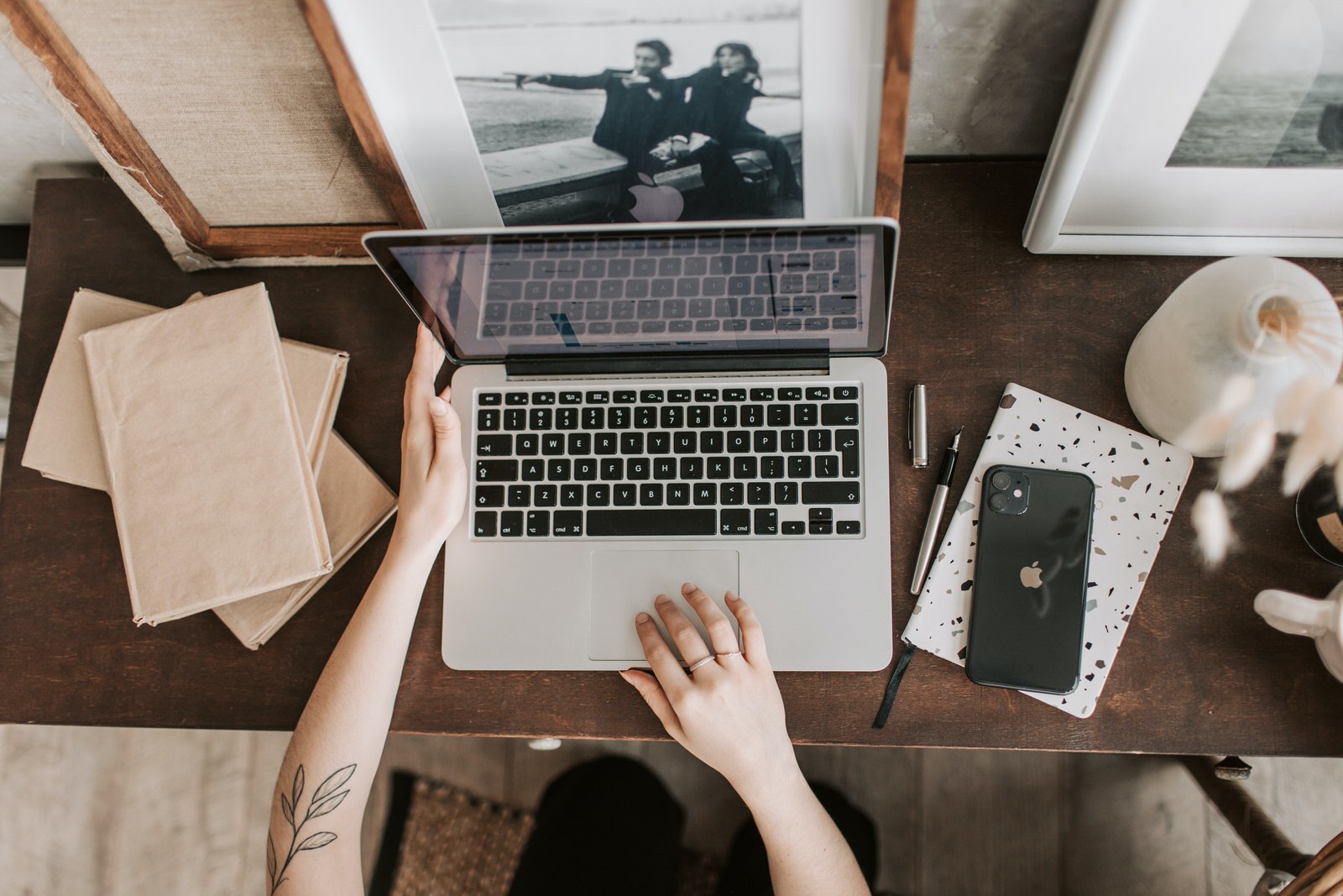 A photographer working on a laptop at a home desk, backing up photos on cloud storage.