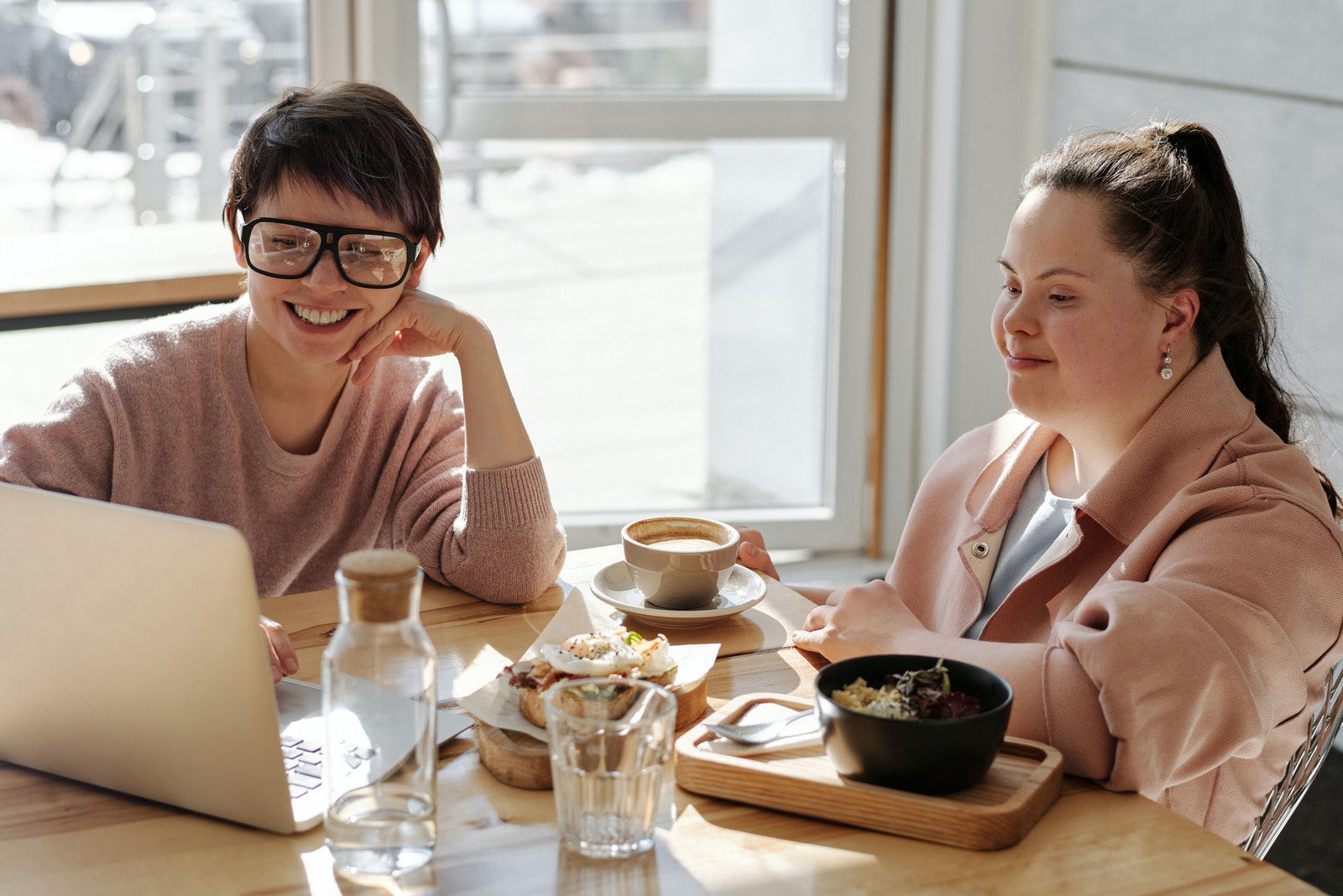 A female photographer using her laptop to show photos to a female client at a lunch meeting.