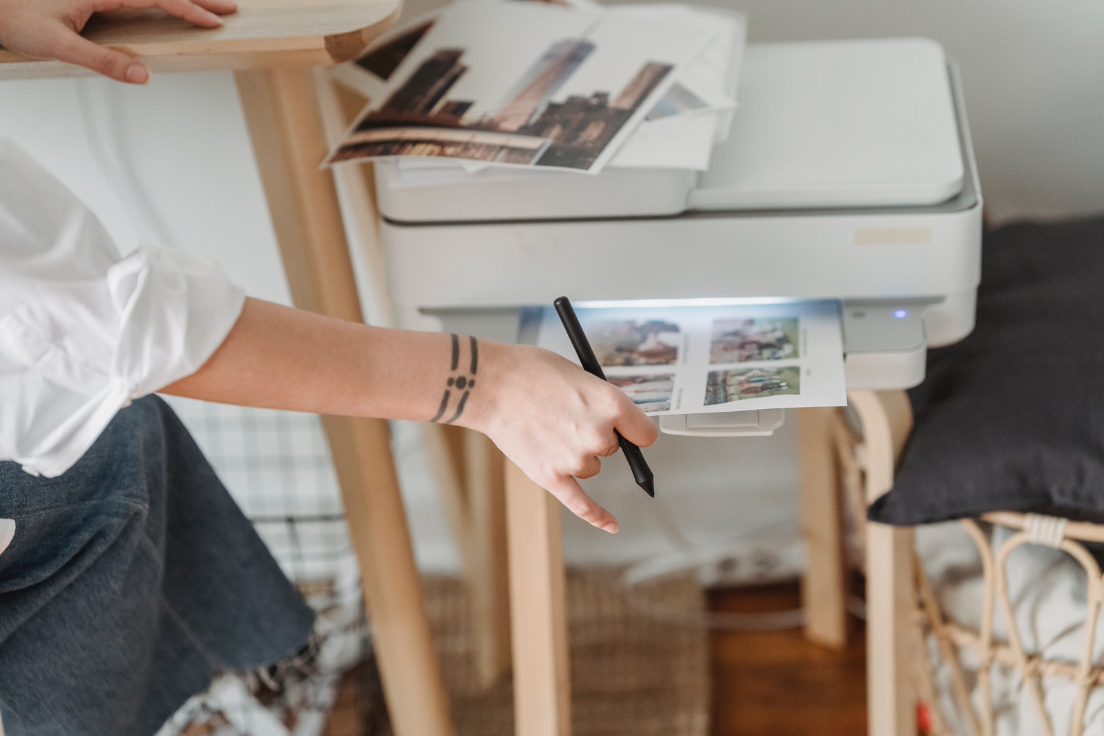 A woman printing out photos at home to prepare her clients’ photo print orders.