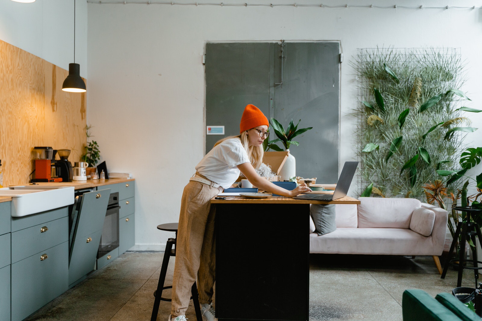 A photographer with a red beanie hat using laptop at home to create social media content.