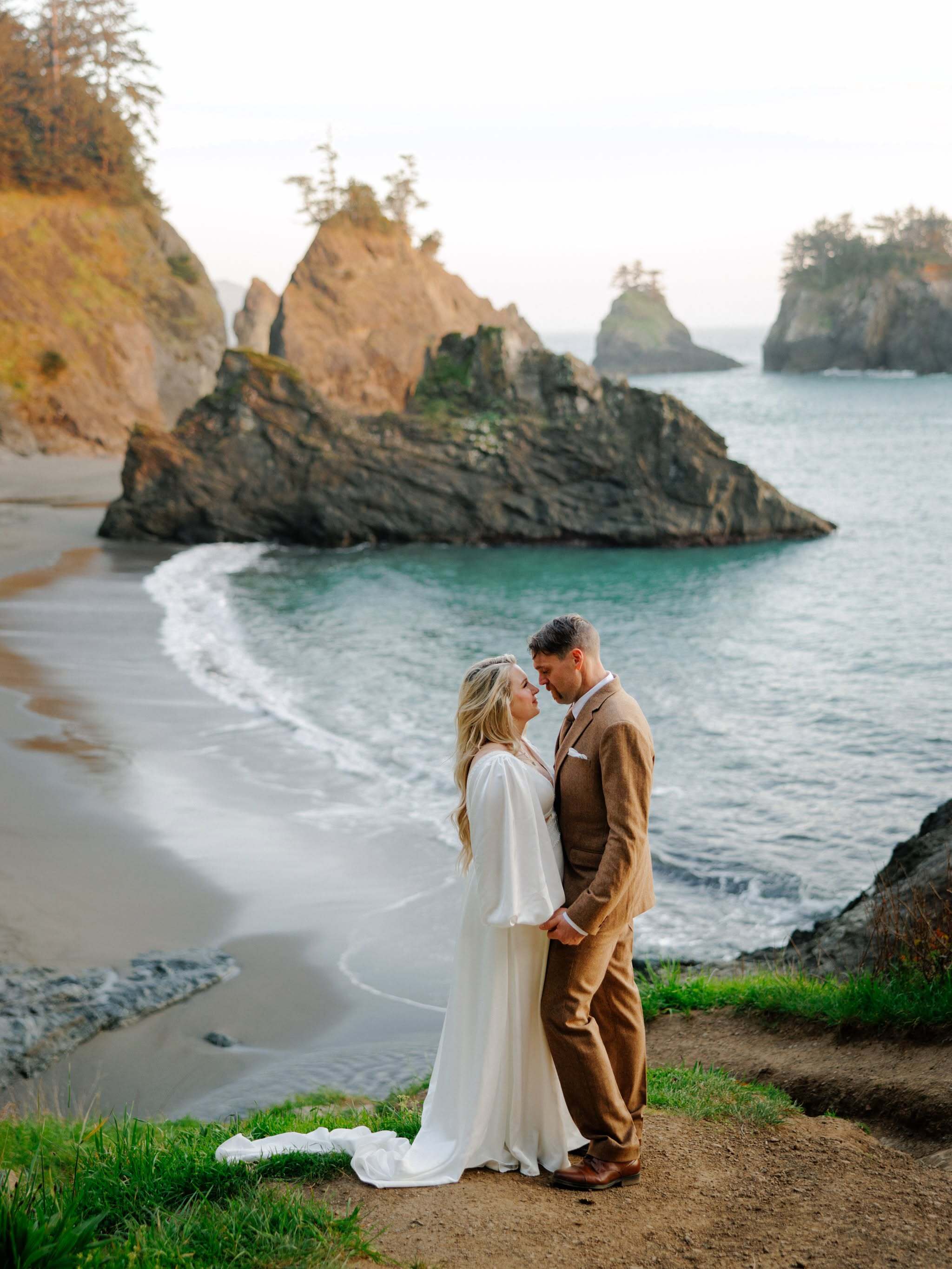 Bride and groom embracing on a beach at sunset with mountain backdrop, wedding photo culled and edited in Narrative to enhance golden hour tones.