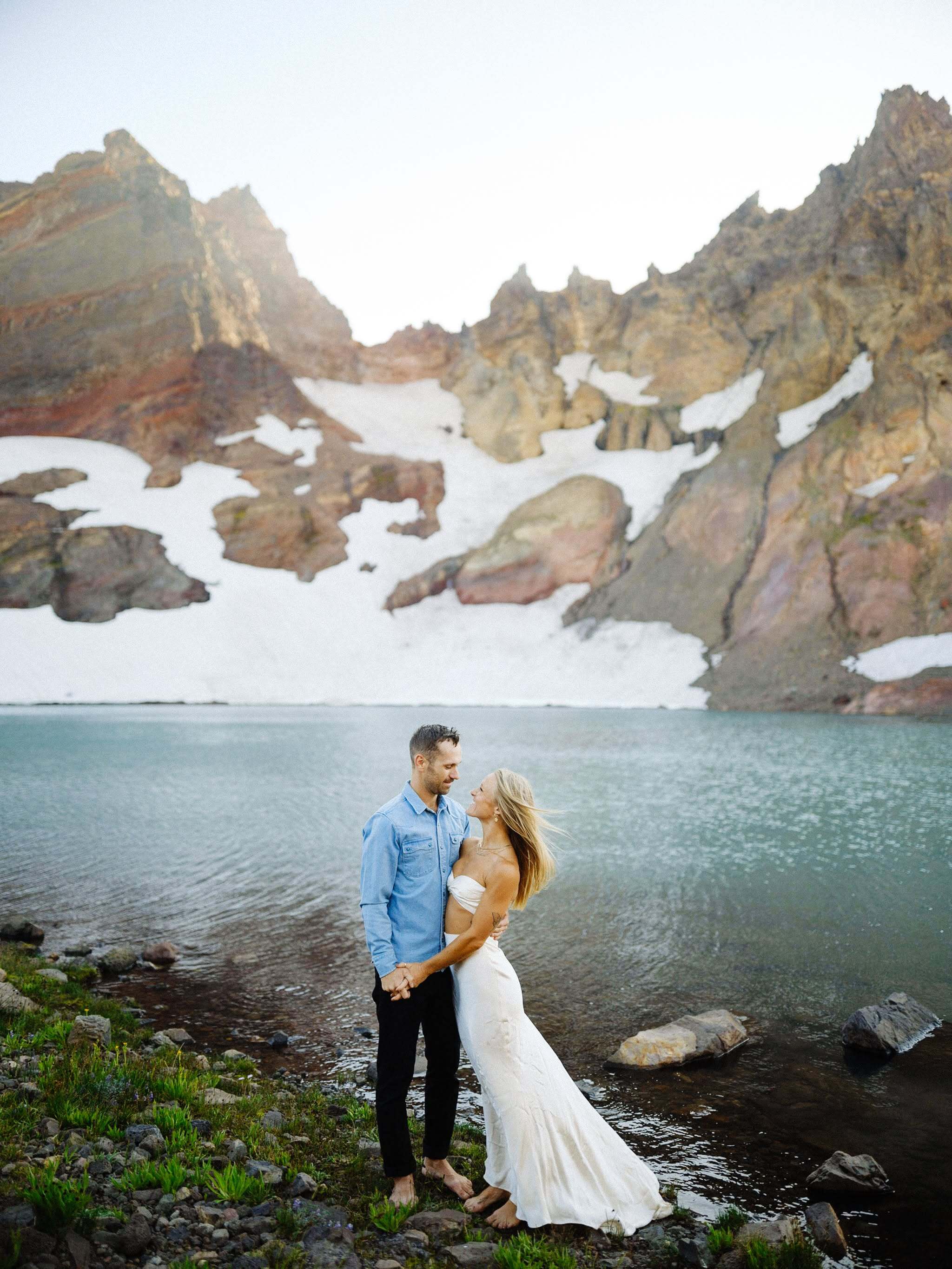 Engagement photo of couple standing beside a lake, photographed by Ely and enhanced with AI editing in Narrative.