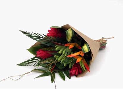 Fresh bouquet of red roses and mixed greenery wrapped in brown paper on a white background, ideal for romantic occasions or as a gift.