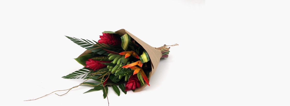 Vibrant bouquet of red roses and tropical greenery wrapped for a special occasion.