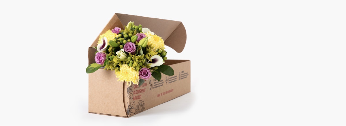 Vibrant floral arrangement featuring purple roses and yellow chrysanthemums in a gift box.