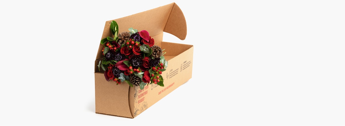 Charming floral arrangement featuring roses, greens, and pinecones in a rustic box.