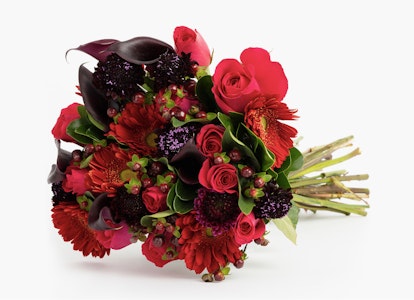 Vibrant bouquet featuring a mix of red roses, gerberas, and other flowers with green foliage accents on a white background, perfect for romantic gestures or special occasions.