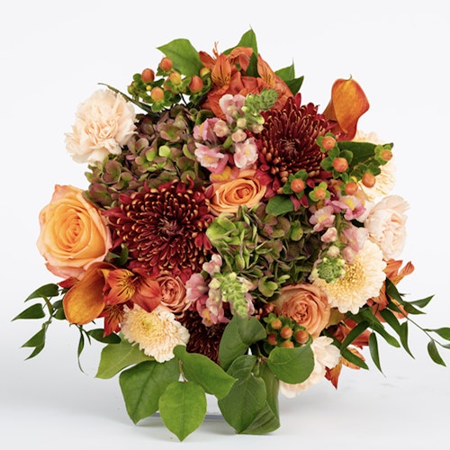 Vibrant bouquet of fresh flowers featuring orange roses, dark red chrysanthemums, and lush green foliage, set against a white background for a striking contrast.