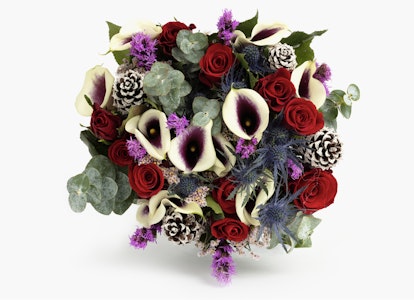 A vibrant bouquet featuring a mix of red roses, purple flowers, exotic calla lilies, and pine cones, elegantly assembled with lush greenery on a white background.