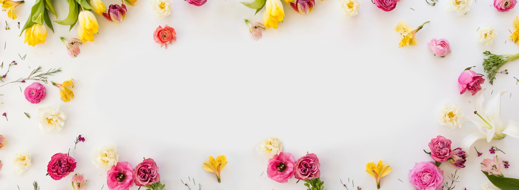 A vibrant floral arrangement featuring mixed roses, tulips, and daisies on a light background.