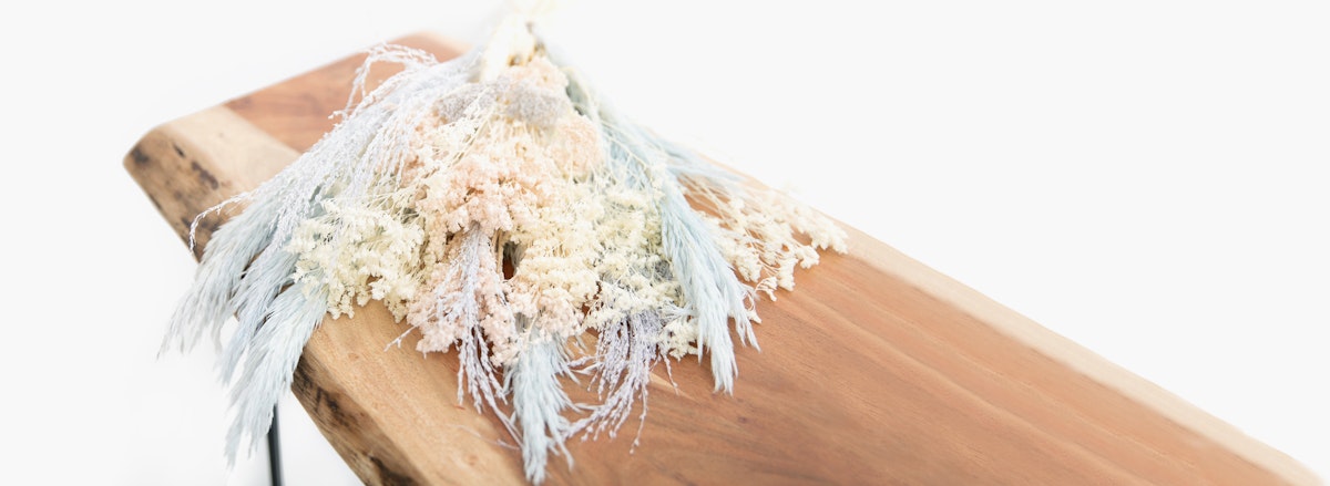 Dried floral arrangement featuring soft pastel hues on a rustic wooden table.