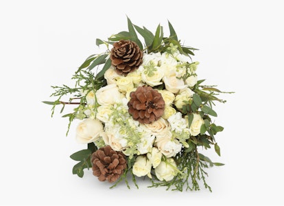 Elegant floral arrangement with white blooms and green foliage accented by pine cones on a light background, perfect for weddings or festive occasions.