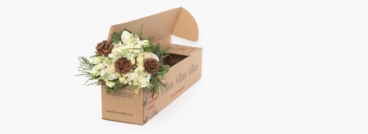 Elegant floral arrangement in a sustainable box, featuring white blooms and earthy accents.