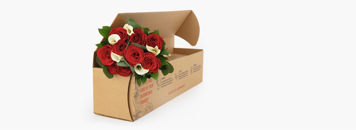 Elegant bouquet of red roses and white calla lilies in a stylish delivery box.