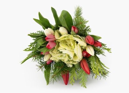 Elegant bouquet of white and pink tulips with lush green leaves and sprigs of evergreens arranged together against a clean white background.