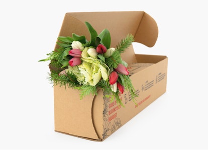 Cardboard box with a fresh bouquet of flowers, featuring pink tulips and green foliage, partially wrapped, ready for delivery on a white background.