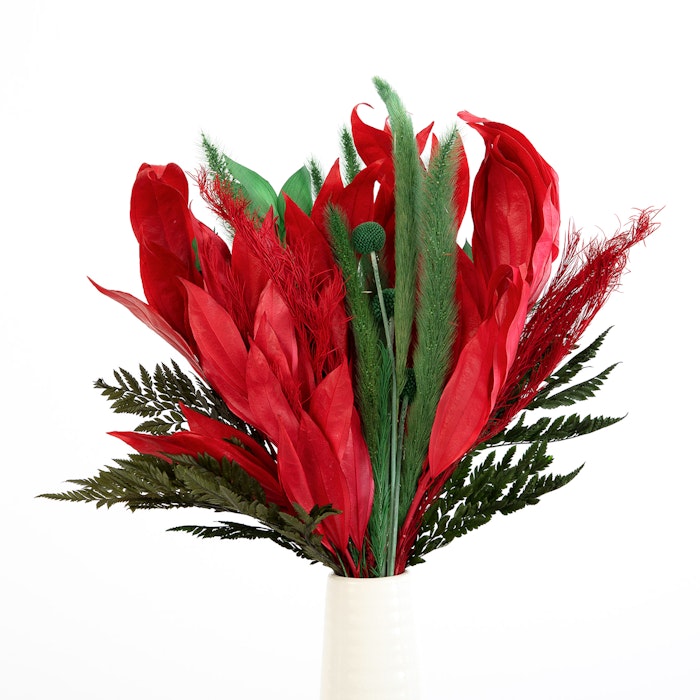 Vibrant bouquet of red feathers and green leaves with contrasting textures in a white vase against a stark white background, creating a bold visual centerpiece.