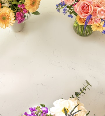 A variety of fresh, colorful flowers arranged in vases displayed on a white surface with ample copy space for text or design elements.