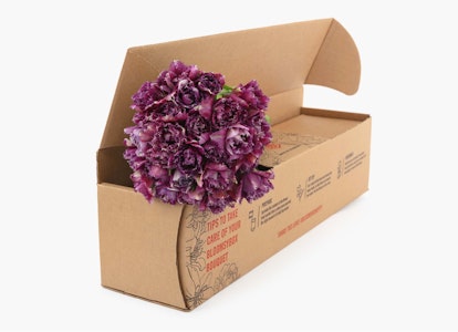 A bunch of fresh purple flowers protruding from an open cardboard box on a clean, white background, illustrating online flower delivery or packaging.