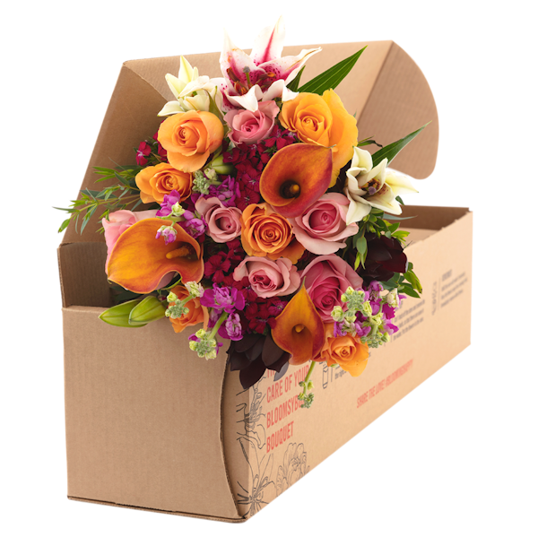 Vibrant assorted flower bouquet with roses, lilies, and other blooms in a brown cardboard box, ready for delivery or gifting, showcasing fresh and colorful floral arrangement.