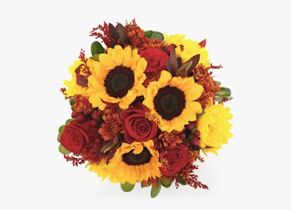Vibrant bouquet of flowers featuring bright sunflowers, deep red roses, and lush greenery on a clean white background, ideal for festive occasions or as a gift.