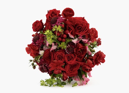Elegant bouquet of red roses and assorted flowers with rich greenery against a white background, ideal for romantic occasions or as a festive gift.