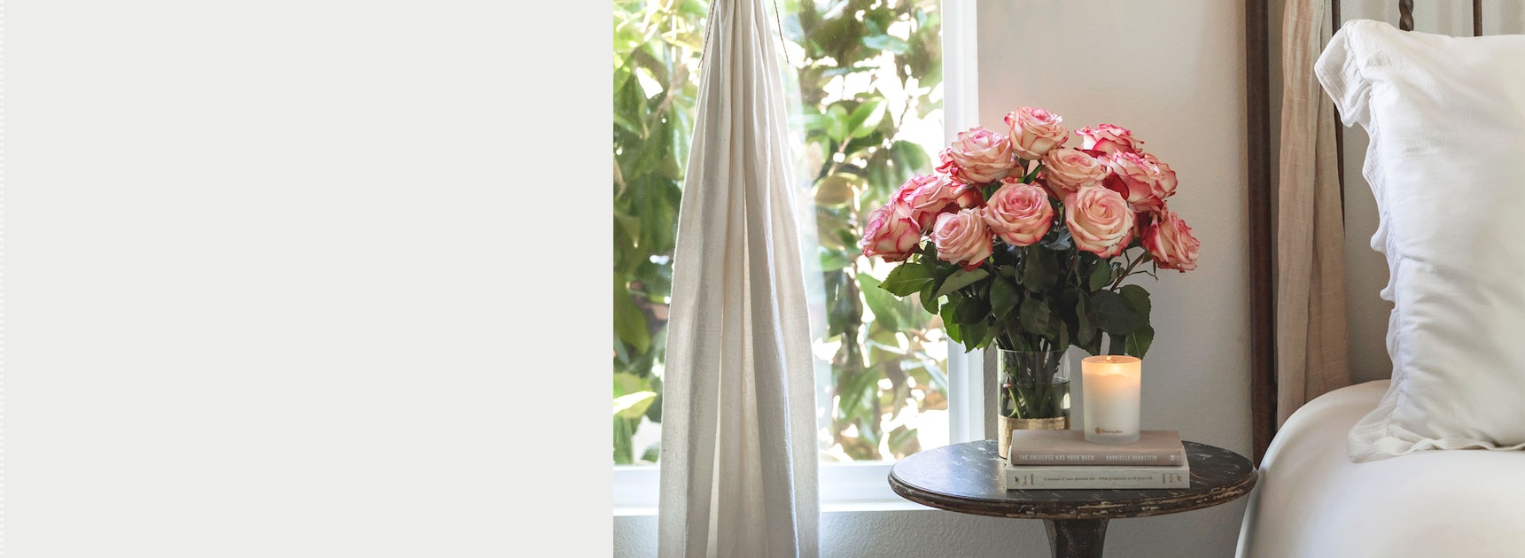 Elegant pink roses in a chic vase on a side table beside a window, enhancing a cozy room ambiance.