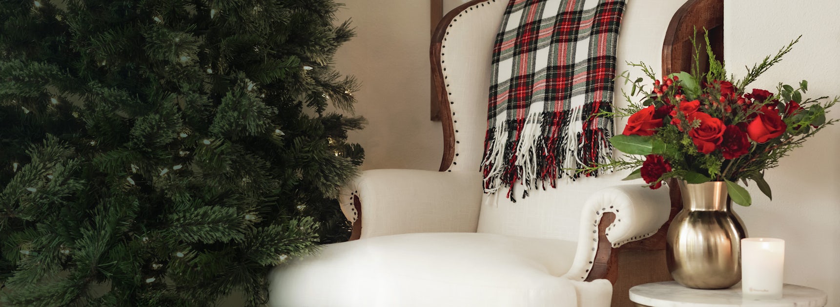 Festively decorated chair with a cozy plaid blanket and a vibrant holiday floral arrangement.