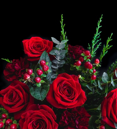 A vibrant bouquet of red roses accented with lush greenery and berries, perfect for gifting.