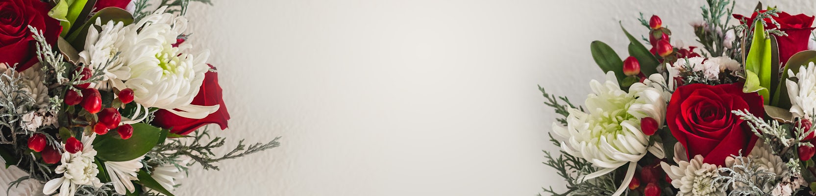 Festive holiday floral arrangement featuring red roses, white chrysanthemums, and greenery.