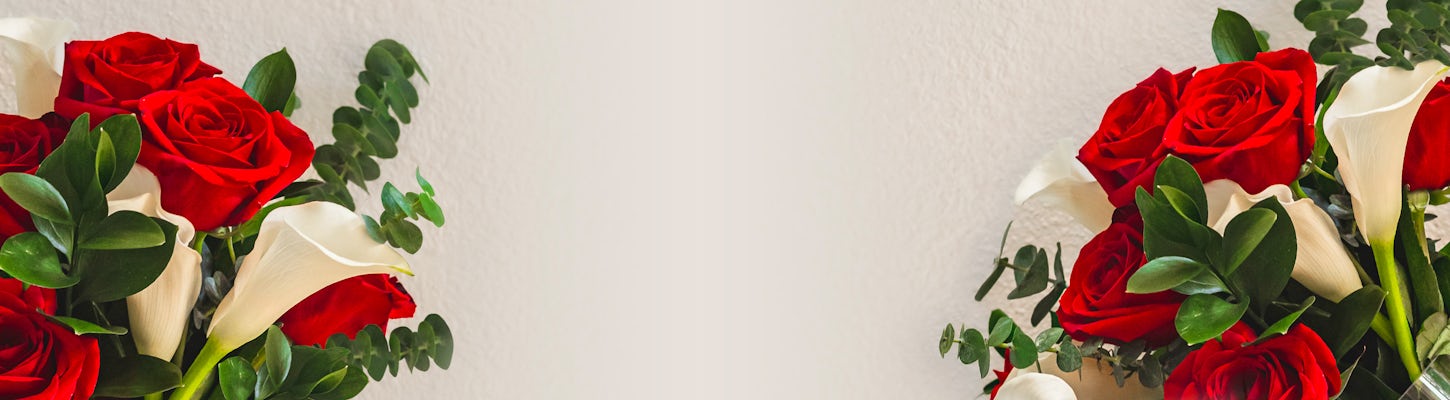 Vibrant bouquet of red roses and white calla lilies, accented with lush greenery.