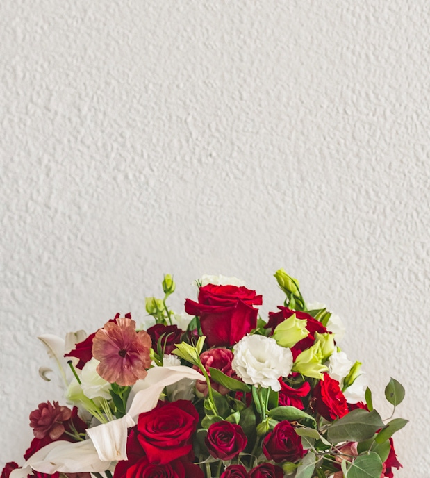 Vibrant bouquet featuring red roses, white lisianthus, and green accents, ideal for celebrations.
