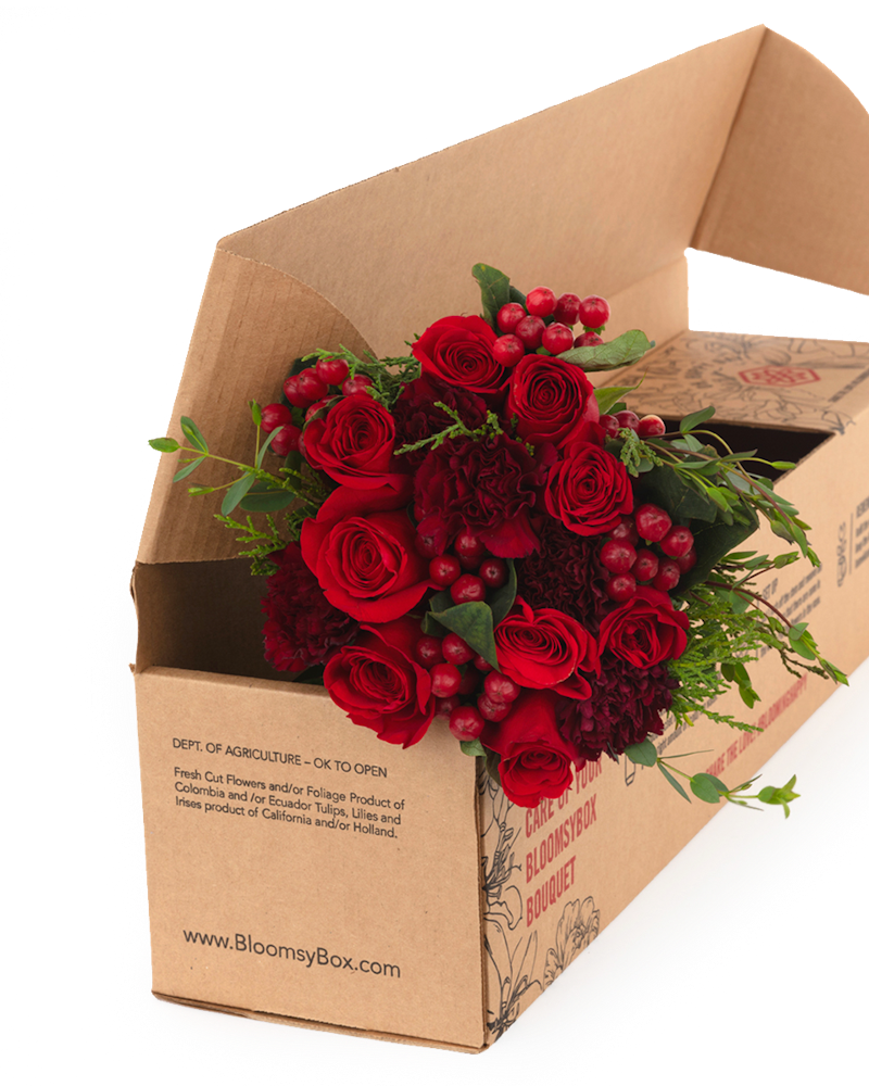 Bouquet of fresh red roses and berries neatly packaged in a BloomzyBox cardboard box, showcasing an elegant, ready-to-deliver floral gift against a transparent background.
