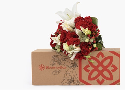 Elegant bouquet of red roses and white lilies with green foliage, neatly arranged and emerging from a decorative BloomsyBox with a distinctive flower logo.